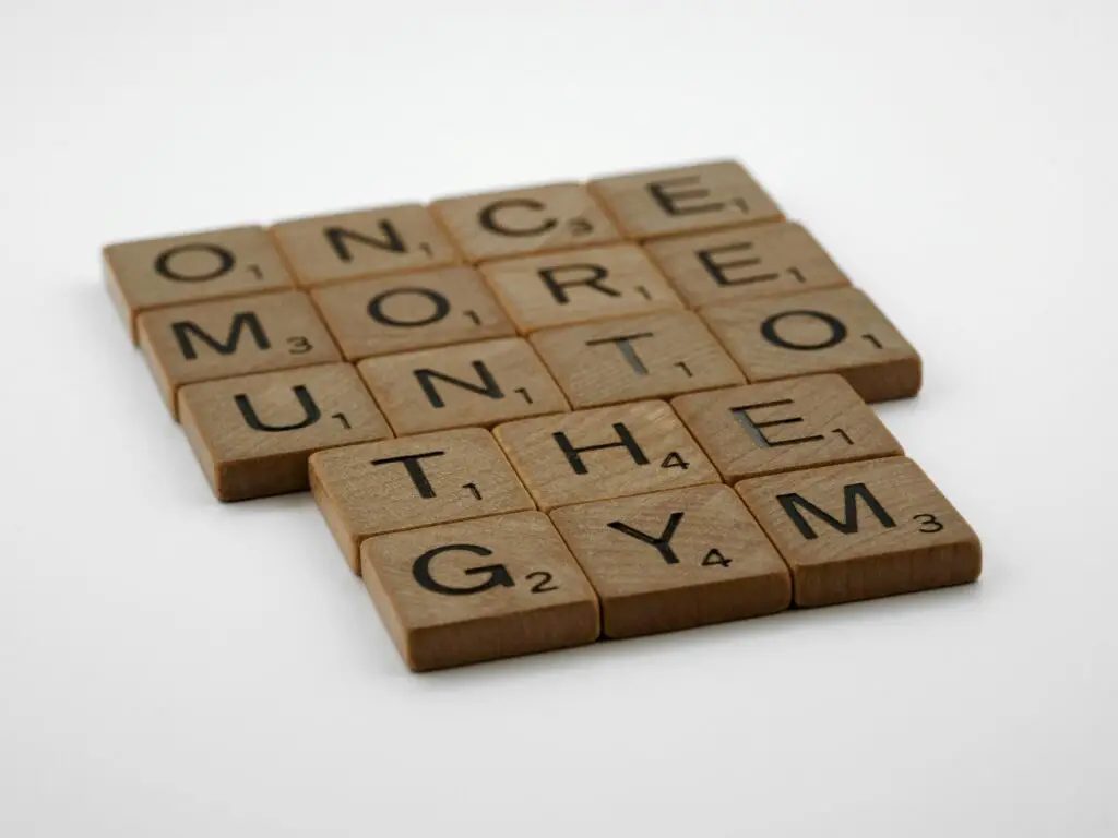 Scrabble tiles forming the motivational phrase 'Once More Unto the Gym' on a white background.